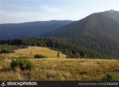 Carpathian mountains (Ukraine) landscape with yellow grass on forefront and tourist tents behind