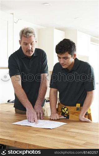 Carpenter And Apprentice Installing Luxury Fitted Kitchen
