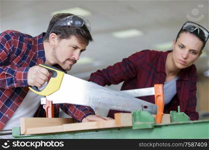 carpenter and apprentice working together in wood workshop