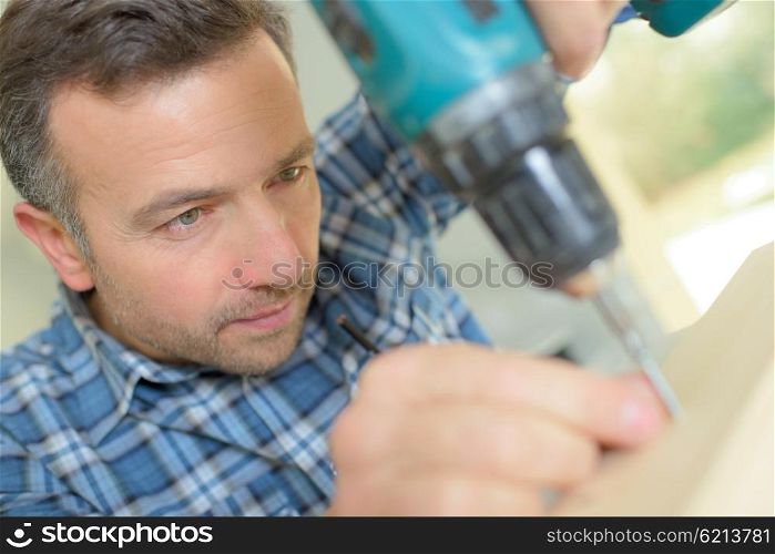 Carpenter carefully drilling a hole