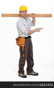 carpenter carrying plank over his shoulder pointing at something