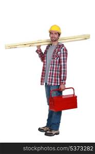 Carpenter carrying planks of wood and tool-box