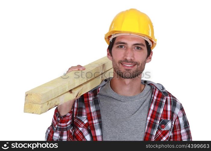 Carpenter carrying planks of wood over shoulder