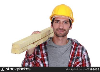Carpenter carrying planks of wood over shoulder