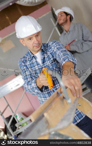 carpenter cutting house roof supports on building site