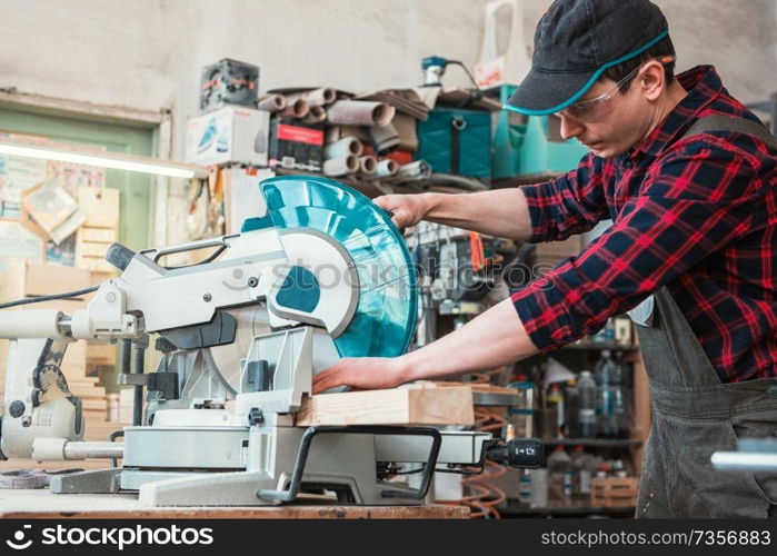 Carpenter cutting wooden board with circular saw. Profession, carpentry and woodwork concept.. Carpenter worker cutting wooden board