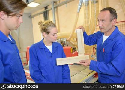 Carpenter demonstrating to two apprentices