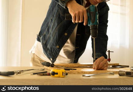 Carpenter drills a hole with an electrical drill on working space