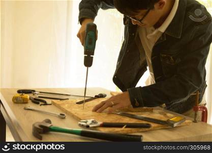 Carpenter drills a hole with an electrical drill on working space