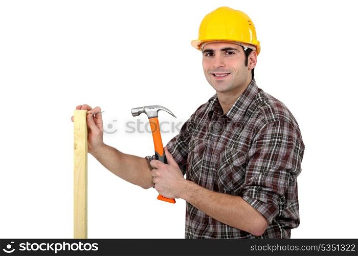 Carpenter driving a nail in a beam, studio shot
