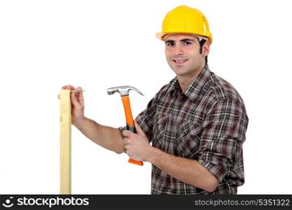 Carpenter driving a nail in a beam, studio shot