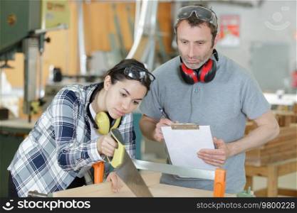 carpenter female apprentice using saw
