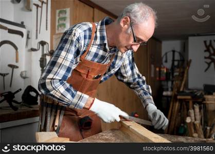 Carpenter filing a plank of wood in his Workshop. High quality photography.. Carpenter filing a plank of wood in his Workshop.