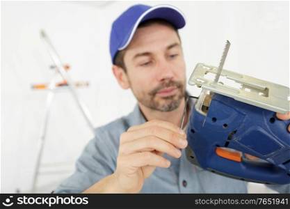 carpenter is holding a jig saw machine in carpentry