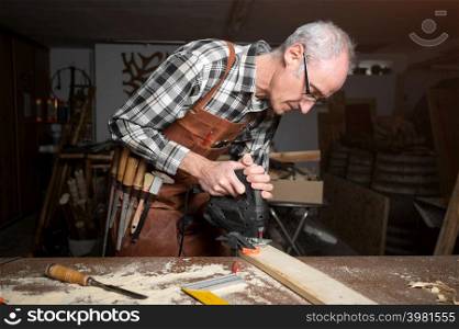 Carpenter is sawing a wood plank with electric jig saw machine in carpentry workshop. Workwood DIY concept. High quality photography.. Carpenter is sawing a wood plank with electric jig saw machine in carpentry workshop. Workwood DIY concept