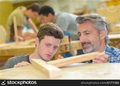 Carpenter looking at his apprentice&rsquo;s work