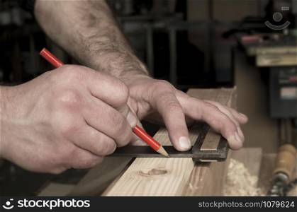 carpenter marking wooden detail with square and red pencil