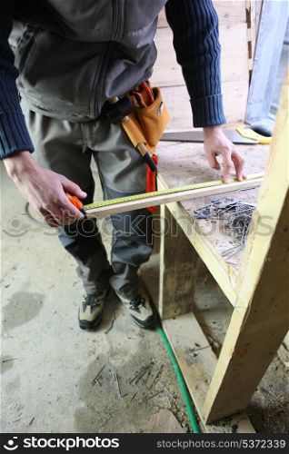 Carpenter measuring plank of wood