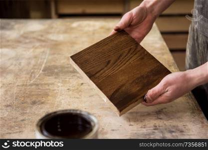 Carpenter painting wooden board in a wooden workshop. Profession, carpentry and woodwork concept.. Carpenter painting wooden
