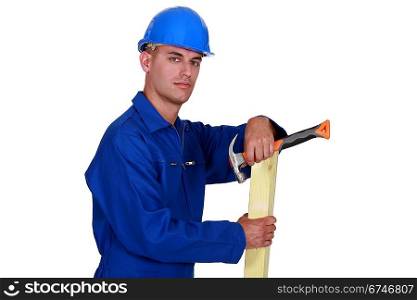 Carpenter posing with plank of wood and hammer