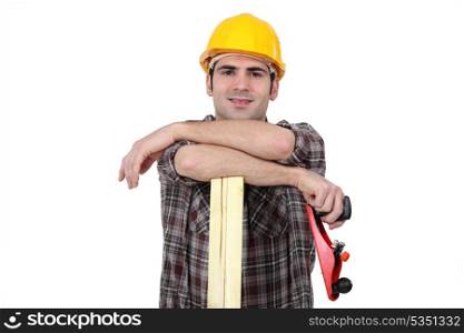 Carpenter posing with plank of wood and plane