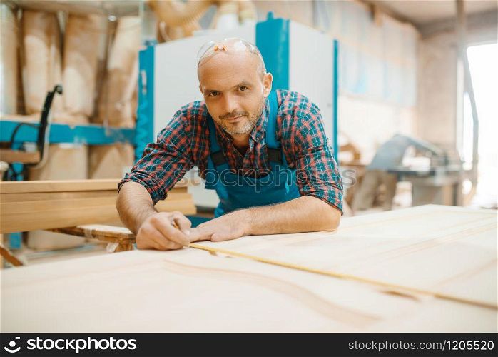 Carpenter processes wooden door, woodworking, lumber industry, carpentry. Wood processing on furniture factory, production of products of natural materials. Carpenter processes wooden door, woodworking