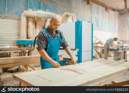 Carpenter processes wooden door, woodworking, lumber industry, carpentry. Wood processing on furniture factory, production of products of natural materials