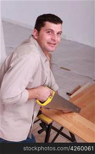 Carpenter sawing wooden flooring