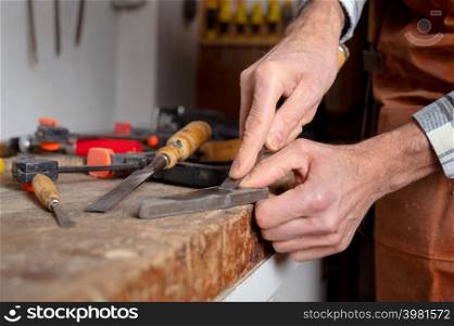 Carpenter sharpening a chisel. woodworking process with hand tools in a carpentry workshop. wood carving concept. High quality photography.. Carpenter sharpening a chisel. woodworking process with hand tools in a carpentry workshop. wood carving concept