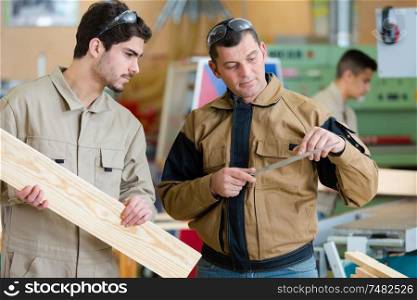 carpenter showing tool to his apprentice