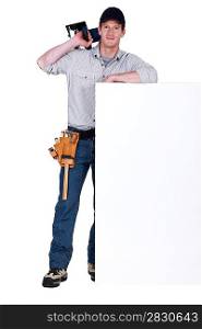 Carpenter stood by blank message board with circular-saw