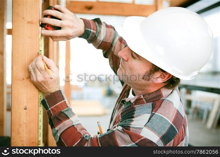 Carpenter taking measurements on a construction site.