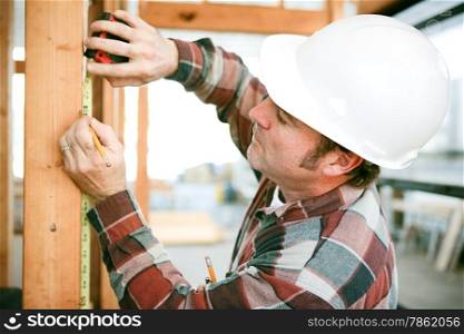 Carpenter taking measurements on a construction site.