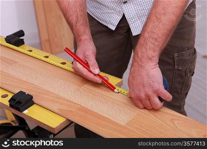 carpenter taking measurements to lay parquet