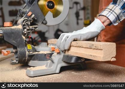 Carpenter using an electric circular saw, cutting piece of wood. High quality photo.. Carpenter using an electric circular saw, cutting piece of wood.
