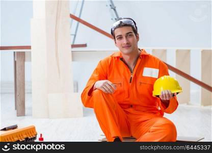 Carpenter wearing yellow hardhat in contractor workshop