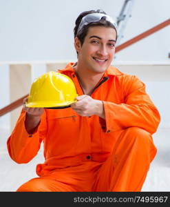 Carpenter wearing yellow hardhat in contractor workshop. The carpenter wearing yellow hardhat in contractor workshop