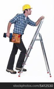 Carpenter with drill climbing step-ladder
