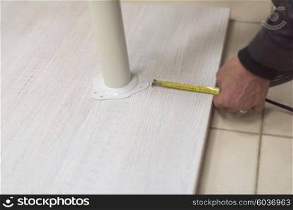 carpenter worker measuring distance for drilling holes in new furniture