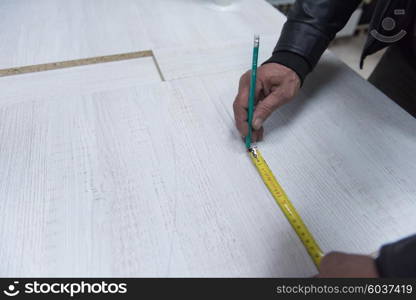 carpenter worker measuring distance for drilling holes in new furniture