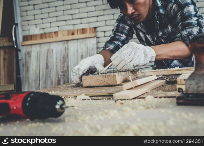 Carpenter working on wood craft at workshop to produce construction material or wooden furniture. The young Asian carpenter use professional tools for crafting. DIY maker and carpentry work concept.