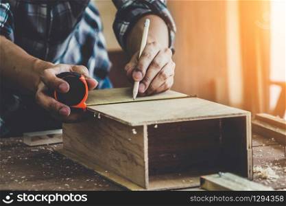 Carpenter working on wood craft at workshop to produce construction material or wooden furniture. The young Asian carpenter use professional tools for crafting. DIY maker and carpentry work concept.