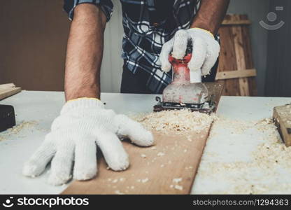 Carpenter working on wood craft at workshop to produce construction material or wooden furniture. The young Asian carpenter use professional tools for crafting. DIY maker and carpentry work concept.