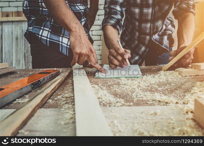 Carpenter working on wood craft at workshop to produce construction material or wooden furniture. The young Asian carpenter use professional tools for crafting. DIY maker and carpentry work concept.