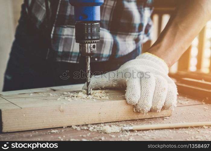 Carpenter working on wood craft at workshop to produce construction material or wooden furniture. The young Asian carpenter use professional tools for crafting. DIY maker and carpentry work concept.