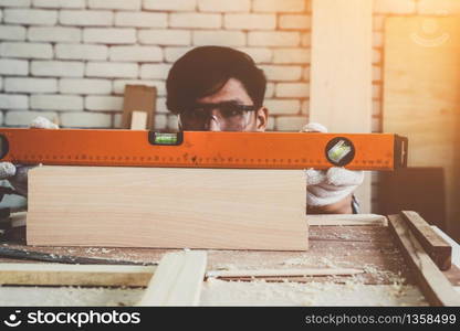 Carpenter working on wood craft at workshop to produce construction material or wooden furniture. The young Asian carpenter use professional tools for crafting. DIY maker and carpentry work concept.