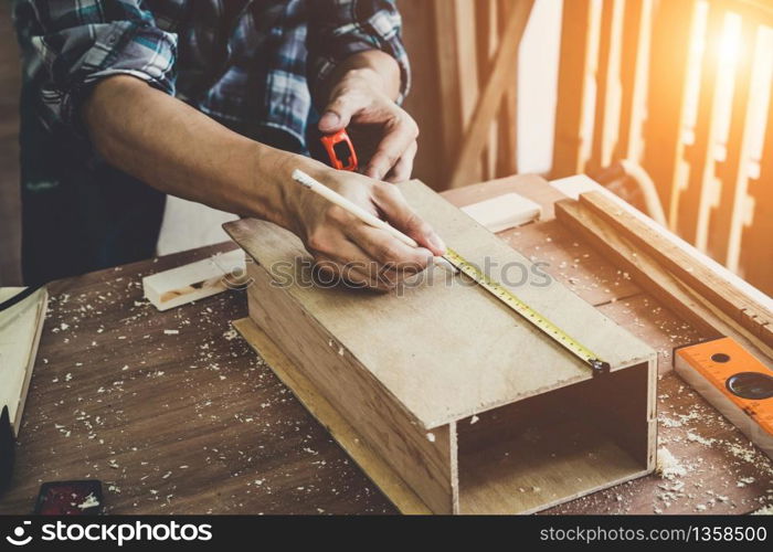 Carpenter working on wood craft at workshop to produce construction material or wooden furniture. The young Asian carpenter use professional tools for crafting. DIY maker and carpentry work concept.