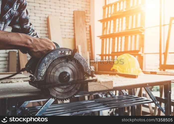 Carpenter working on wood craft at workshop to produce construction material or wooden furniture. The young Asian carpenter use professional tools for crafting. DIY maker and carpentry work concept.