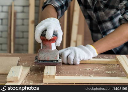 Carpenter working on wood craft at workshop to produce construction material or wooden furniture. The young Asian carpenter use professional tools for crafting. DIY maker and carpentry work concept.