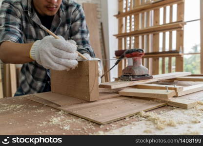 Carpenter working on wood craft at workshop to produce construction material or wooden furniture. The young Asian carpenter use professional tools for crafting. DIY maker and carpentry work concept.